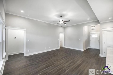 A spacious room with wood flooring and a ceiling fan.