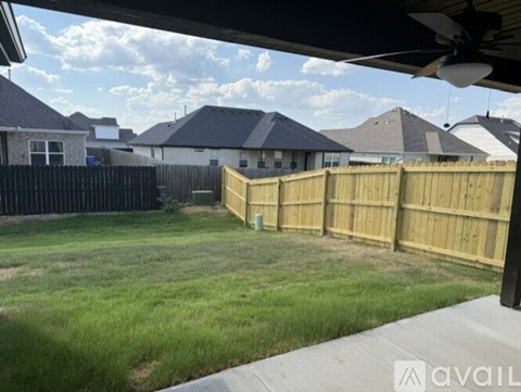A backyard with a wooden fence and a grassy area.