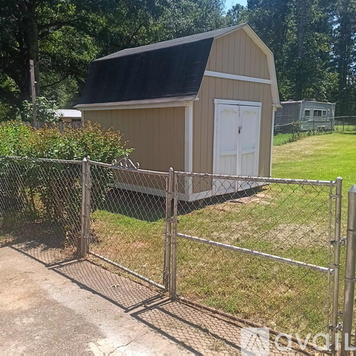 A shed with a white door is surrounded by a chain link fence.