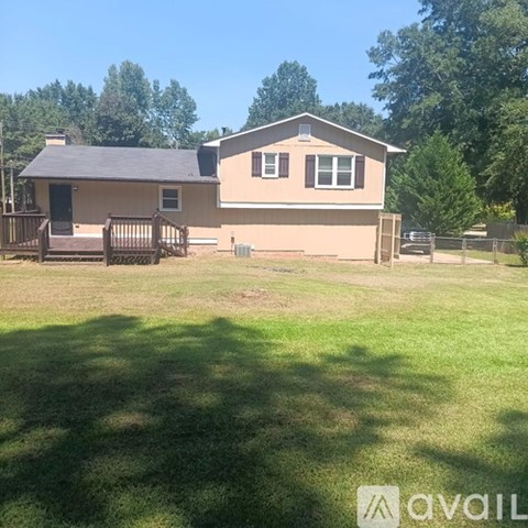 A house with a brown roof and a deck in the front yard.