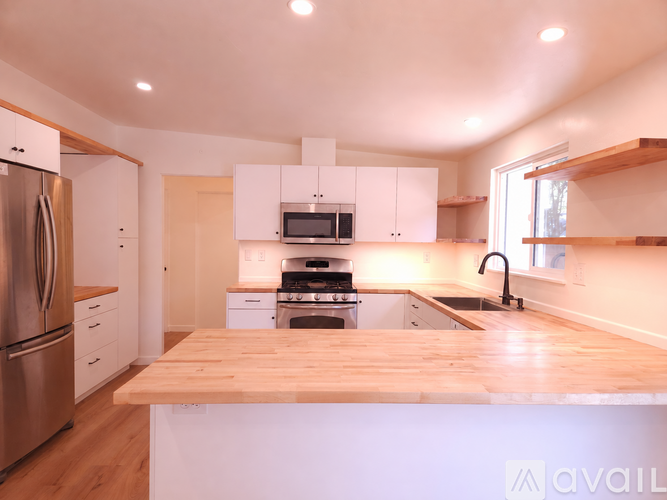 A kitchen with a wooden counter top and stainless steel appliances.