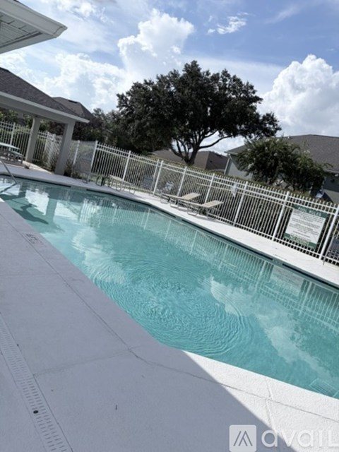 A pool with a white fence and a tree in the background.