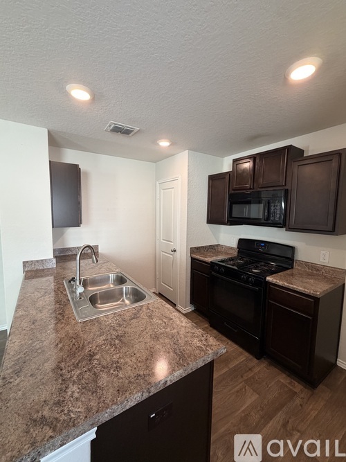 A kitchen with brown cabinets and a granite countertop.