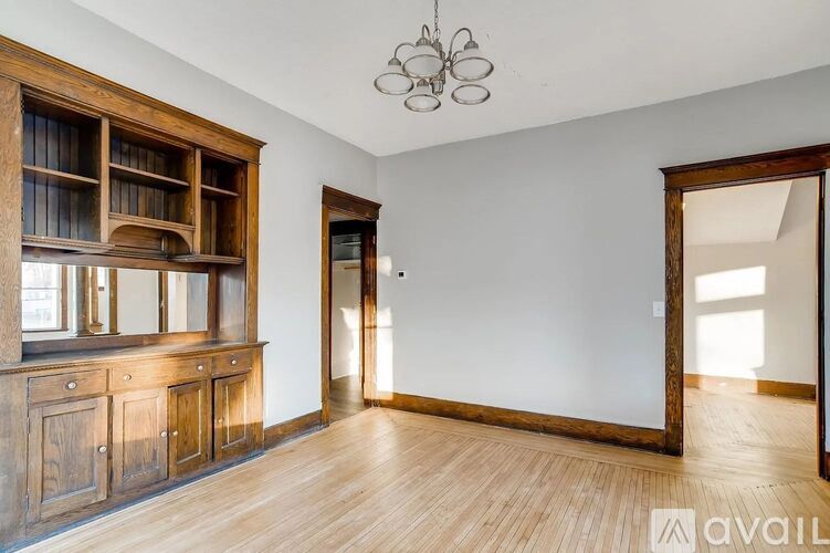 A room with wooden floors and furniture, and a chandelier hanging from the ceiling.