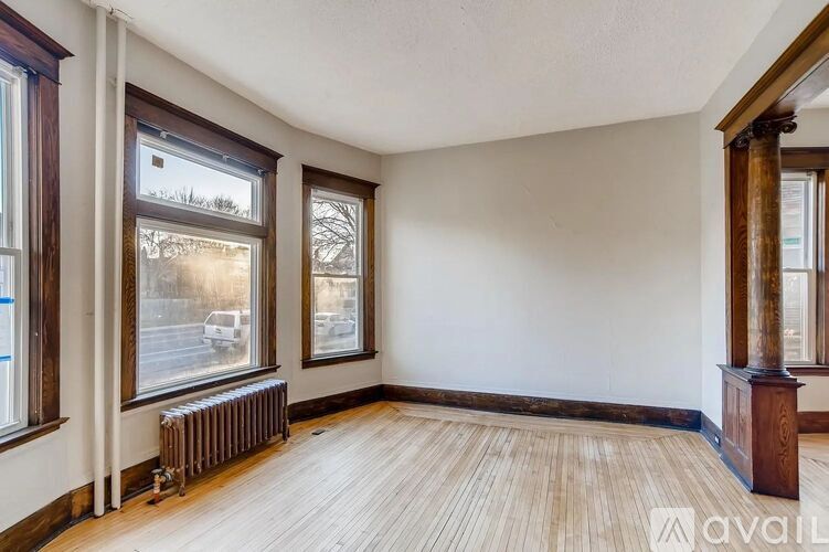 A room with wooden floors and three windows.