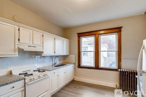 A kitchen with white cabinets and a granite countertop.