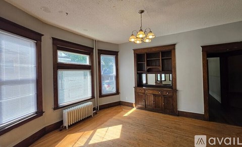 A room with wooden floors and a chandelier hanging from the ceiling.