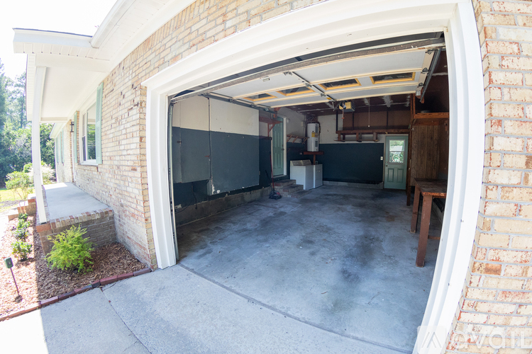 A garage with a white door is attached to a brick house.
