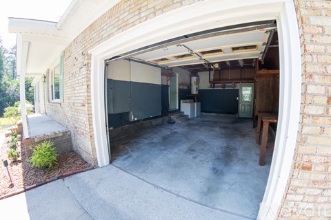 A garage with a white door is attached to a brick house.