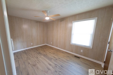 A room with wooden walls and floor and a window.