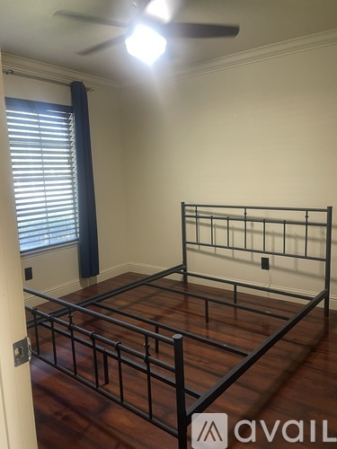 A bedroom with a metal frame bed and a window with blinds.
