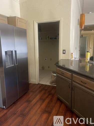 A kitchen with a stainless steel refrigerator and wooden floors.