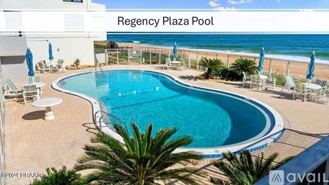 A large outdoor pool surrounded by beach chairs and palm trees.