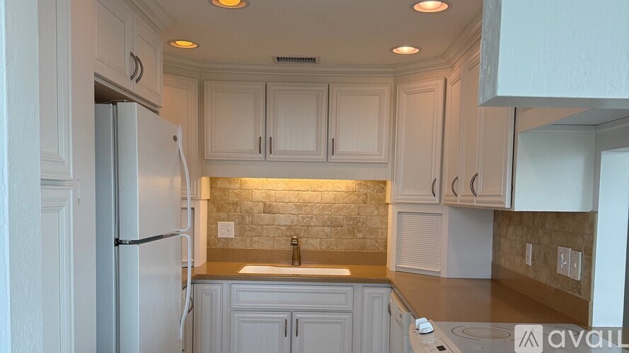 A kitchen with white cabinets and a refrigerator.