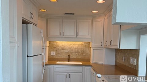 A kitchen with white cabinets and a refrigerator.