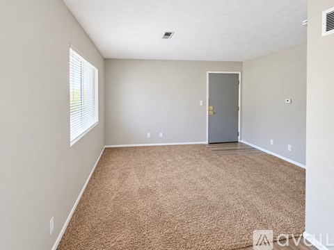 A room with a carpeted floor and a door.