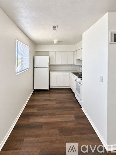 A kitchen with white appliances and wooden floors.