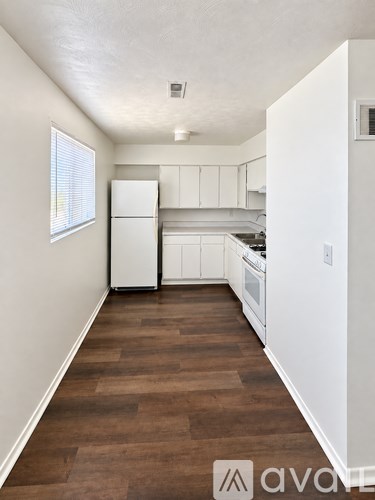 A kitchen with white appliances and wooden floors.