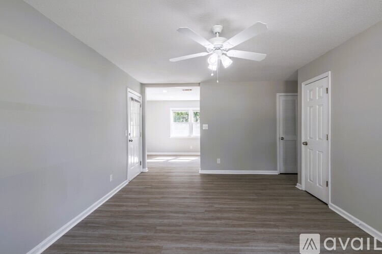 A spacious room with a ceiling fan and light, and a door leading to another room.