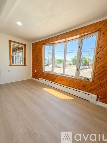 A room with wooden walls and a large window with a view of the street outside.
