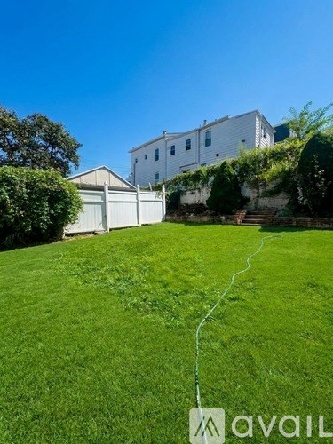 A grassy area with a white fence and a house in the background.