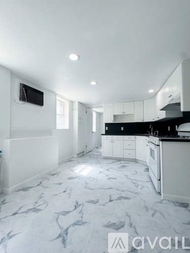 A kitchen with white cabinets and a marble floor.