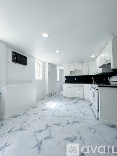 A kitchen with white cabinets and a marble floor.