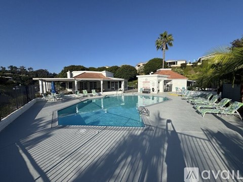 A large outdoor swimming pool surrounded by lounge chairs and a building in the background.