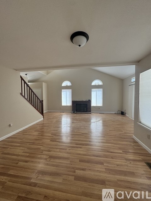 A spacious living room with wooden flooring and a staircase.