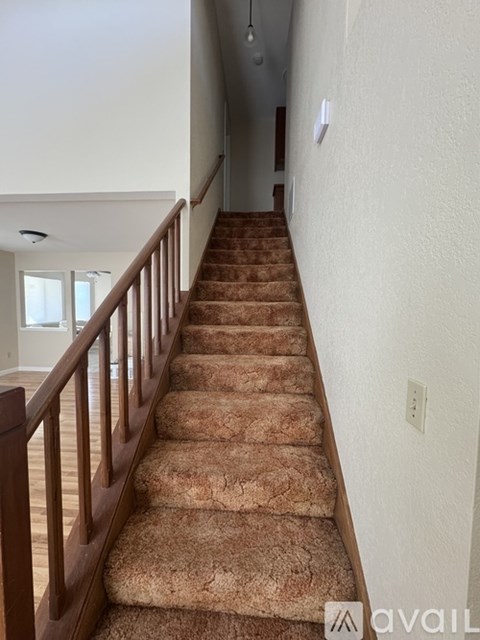 A staircase with a brown carpeted runner and wooden balusters.