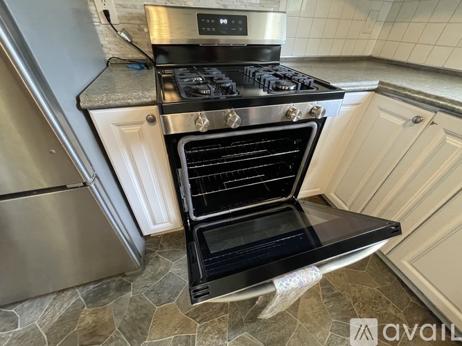 A black oven with the door open is in a kitchen.