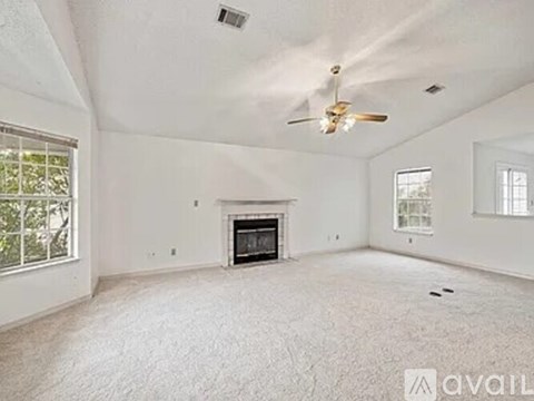 A spacious living room with a fireplace and a ceiling fan.