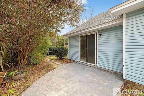 A house with a blue siding and a grey roof with a sliding glass door.