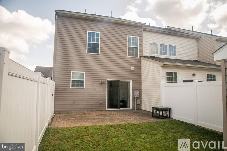 A house with a brown exterior and a white fence is for sale.