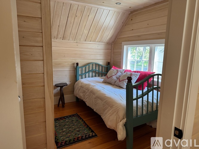A bedroom with a bed, a small table, and a window.