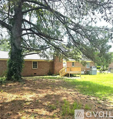 A tree in front of a house with a grassy area in front of it.