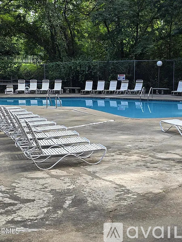A pool with chairs around it and a sign in the background.