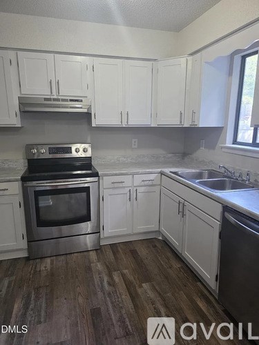 A kitchen with white cabinets and a stove top oven.