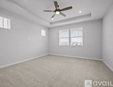 A spacious room with a ceiling fan and carpeted floor.