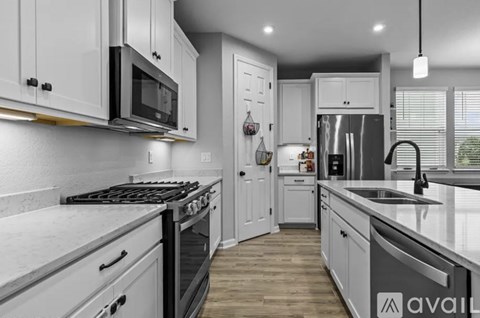 A modern kitchen with white cabinets and stainless steel appliances.