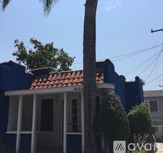 A blue house with a red tile roof and a white door.