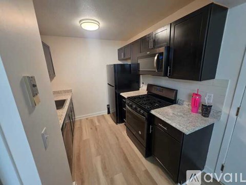 A kitchen with black appliances and wooden floors.