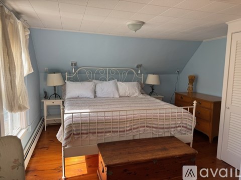 A bedroom with a bed, nightstands, and a chair.