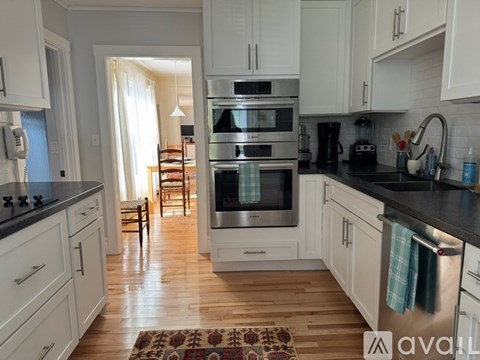 A kitchen with wooden floors and white cabinets.