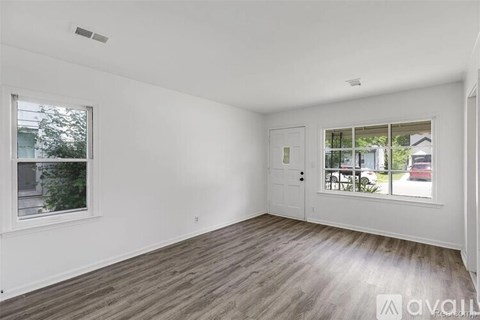 A spacious room with wooden flooring and a large window.