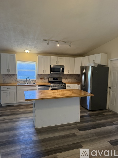 A kitchen with a wooden island and stainless steel appliances.