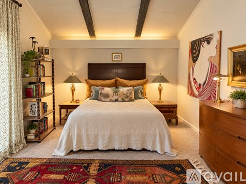 A bedroom with a large bed, a bookshelf, and a painting on the wall.