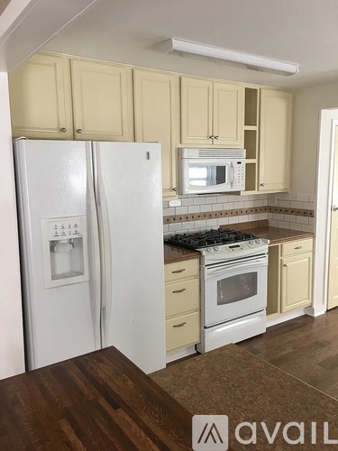A kitchen with white appliances and wooden cabinets.