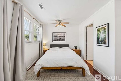 A bedroom with a bed, a ceiling fan, and a window with curtains.