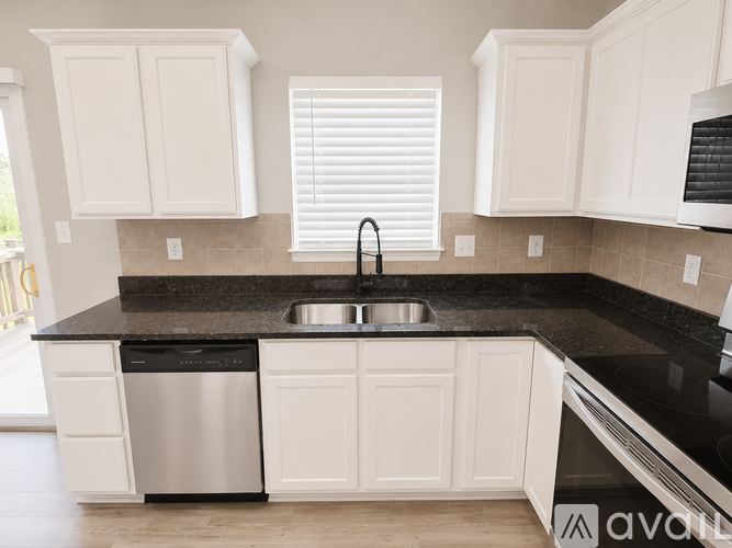 A kitchen with white cabinets and a black countertop.